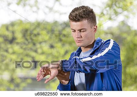 Fit young man checking time at park View Large Photo Image Stock Image - Fit young man checking time at park. Fotosearch