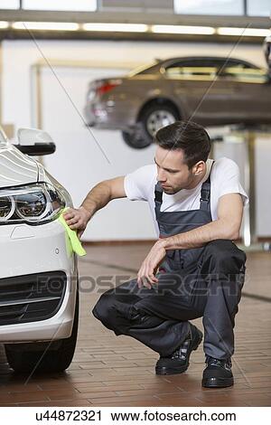 Stock Image - Full length of automobile mechanic cleaning car in workshop. Fotosearch