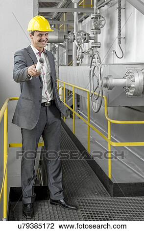 Full length of confident young male architect holding rolled up blueprint in industry View Large Photo Image Stock Image - Full length of confident young male architect holding rolled up blueprint in industry. Fotosearch