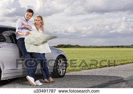 Full length of couple with map discussing direction while leaning on car at countryside View Large Photo Image Stock Photo - Full length of couple with map discussing direction while leaning on car at countryside. Fotosearch