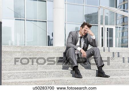Full length of depressed businessman sitting on steps outside office View Large Photo Image Stock Image - Full length of depressed businessman sitting on steps outside office. Fotosearch