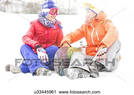 Full length of female friends with snowboard relaxing on snow View Large Photo Image Stock Image - Full length of female friends with snowboard relaxing on snow. Fotosearch