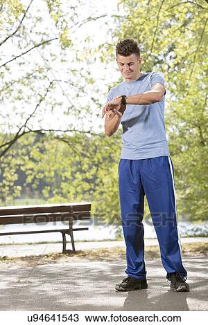 Full length of fit man checking time in park View Large Photo Image Stock Image - Full length of fit man checking time in park. Fotosearch
