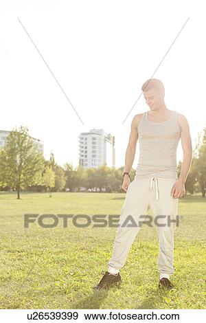 Full length of fit man standing in park View Large Photo Image Stock Photo - Full length of fit man standing in park. Fotosearch