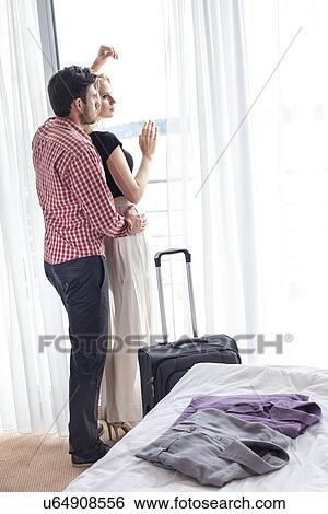 Full length of loving young couple looking through window in hotel room View Large Photo Image Stock Photograph - Full length of loving young couple looking through window in hotel room. Fotosearch