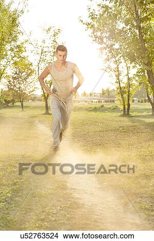 Full length of man listening music while running in park View Large Photo Image Picture - Full length of man listening music while running in park. Fotosearch