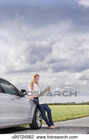 Full length of mid adult woman leaning on car while reading map at countryside View Large Photo Image Stock Image - Full length of mid adult woman leaning on car while reading map at countryside. Fotosearch