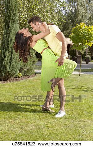 Stock Image - Full length of romantic young couple dancing in park. Fotosearch