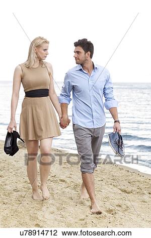 Full length of romantic young couple holding hands and walking on beach View Large Photo Image Stock Image - Full length of romantic young couple holding hands and walking on beach. Fotosearch