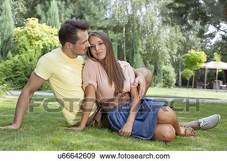 Full length of romantic young couple relaxing on grass in park View Large Photo Image Stock Photo - Full length of romantic young couple relaxing on grass in park. Fotosearch