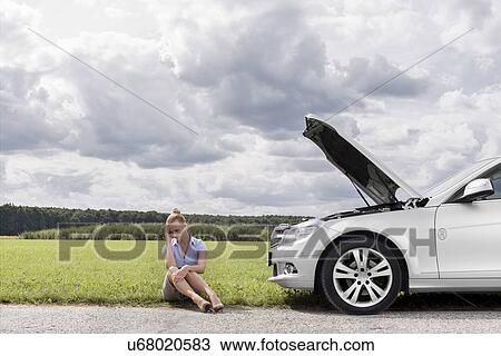 Full length of sad businesswoman sitting by broken down car at countryside View Large Photo Image Stock Image - Full length of sad businesswoman sitting by broken down car at countryside. Fotosearch