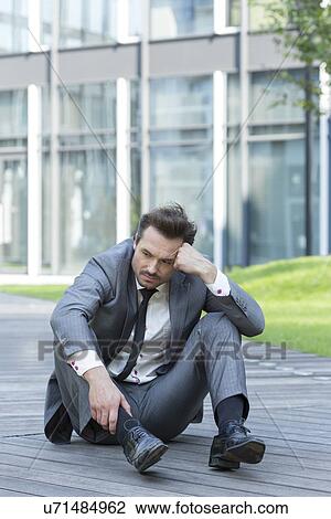 Full length of stressed businessman sitting on path outside office View Large Photo Image Stock Image - Full length of stressed businessman sitting on path outside office. Fotosearch