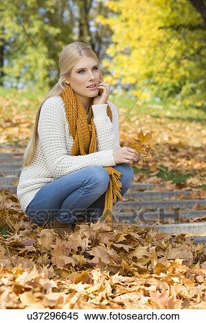 Full length of thoughtful young woman crouching on steps in park View Large Photo Image Stock Photography - Full length of thoughtful young woman crouching on steps in park. Fotosearch