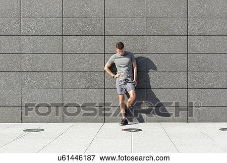 Full length of tired sporty man leaning on tiled wall View Large Photo Image Stock Photo - Full length of tired sporty man leaning on tiled wall. Fotosearch