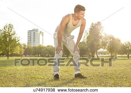 Full length of tired young man standing in park after jogging View Large Photo Image Stock Photo - Full length of tired young man standing in park after jogging. Fotosearch