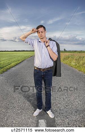 Full length of tired young man standing on empty rural road View Large Photo Image Stock Photography - Full length of tired young man standing on empty rural road. Fotosearch