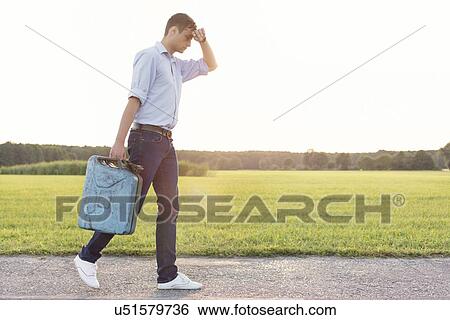 Full length of tired young man with gas can walking on rural road View Large Photo Image Stock Photograph - Full length of tired young man with gas can walking on rural road. Fotosearch