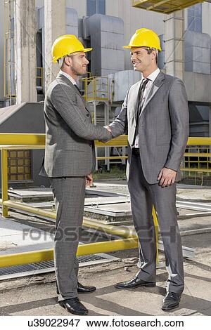Full length of two architects greeting on construction site View Large Photo Image Stock Photo - Full length of two architects greeting on construction site. Fotosearch