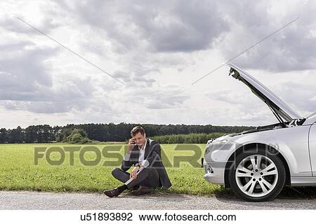 Full length of unhappy young businessman using cell phone by broken down car at countryside View Large Photo Image Stock Image - Full length of unhappy young businessman using cell phone by broken down car at countryside. Fotosearch