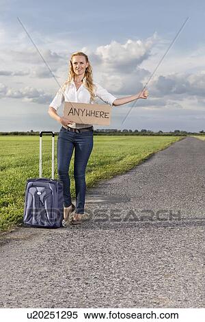 Full length of woman hitching while holding anywhere sign on countryside View Large Photo Image Stock Photography - Full length of woman hitching while holding anywhere sign on countryside. Fotosearch