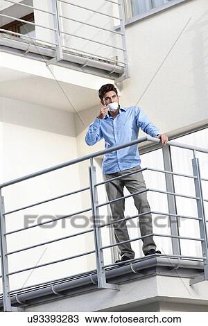 Full length of young businessman drinking coffee at hotel balcony View Large Photo Image Stock Image - Full length of young businessman drinking coffee at hotel balcony. Fotosearch