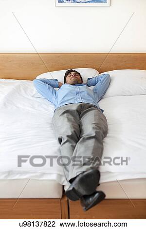 Full length of young businessman sleeping in hotel room View Large Photo Image Stock Image - Full length of young businessman sleeping in hotel room. Fotosearch