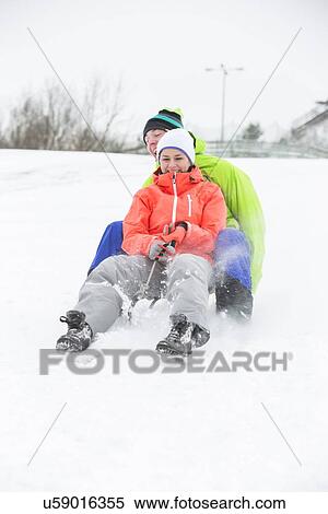 Full length of young couple sledging on snow covered land View Large Photo Image Stock Photography - Full length of young couple sledging on snow covered land. Fotosearch