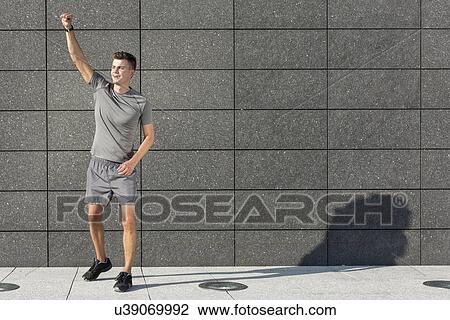Full length of young jogger with clenched fist standing against tiled wall View Large Photo Image Stock Image - Full length of young jogger with clenched fist standing against tiled wall. Fotosearch