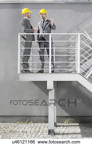 Full length of young male architects communicating on stairway View Large Photo Image Stock Photograph - Full length of young male architects communicating on stairway. Fotosearch