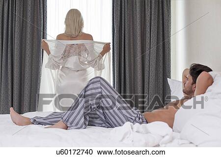 Full length of young man looking at woman removing robe at window View Large Photo Image Stock Image - Full length of young man looking at woman removing robe at window. Fotosearch