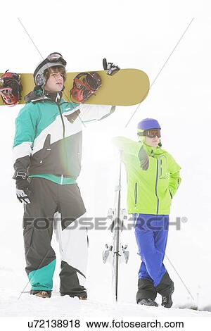 Stock Photo - Full length of young men with snowboards in snow. Fotosearch