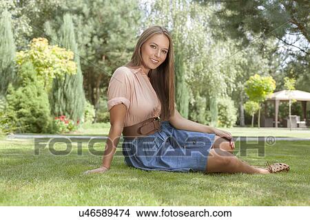 Picture - Full length portrait of beautiful young woman in casuals relaxing in park. Fotosearch
