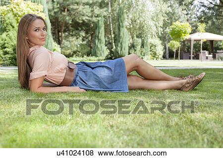 Full length portrait of beautiful young woman lying in park View Large Photo Image Stock Photo - Full length portrait of beautiful young woman lying in park. Fotosearch
