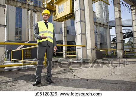 Full length portrait of confident male engineer gesturing outside industry View Large Photo Image Stock Photograph - Full length portrait of confident male engineer gesturing outside industry. Fotosearch