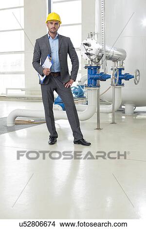 Picture - Full length portrait of confident young male manager with clipboard in industry. Fotosearch