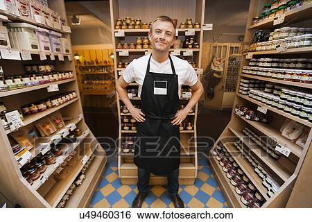 Full length portrait of mid adult salesman standing hands on hips in grocery store View Large Photo Image Stock Photograph - Full length portrait of mid adult salesman standing hands on hips in grocery store. Fotosearch
