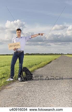 Full length portrait of young man with anywhere sign gesturing on countryside View Large Photo Image Picture - Full length portrait of young man with anywhere sign gesturing on countryside. Fotosearch