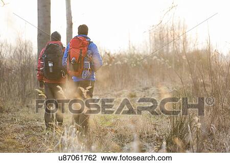 Full length rear view male hikers walking in field View Large Photo Image Stock Image - Full length rear view male hikers walking in field. Fotosearch