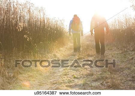 Full length rear view of male hikers walking together in field View Large Photo Image Stock Photo - Full length rear view of male hikers walking together in field. Fotosearch