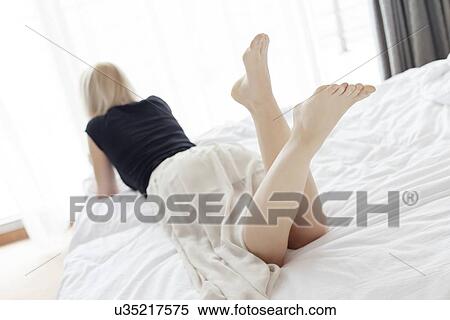 Full length rear view of young woman lying in bed View Large Photo Image Stock Photography - Full length rear view of young woman lying in bed. Fotosearch