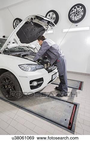 Full length side view of male automobile mechanic repairing car engine in repair shop View Large Photo Image Stock Photo - Full length side view of male automobile mechanic repairing car engine in repair shop. Fotosearch