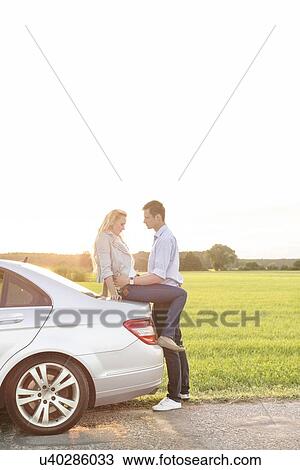 Full length side view of romantic young couple by car at countryside View Large Photo Image Stock Image - Full length side view of romantic young couple by car at countryside. Fotosearch