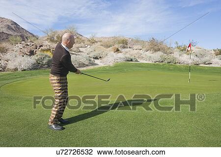 Full length side view of senior male golfer swinging his club at golf course View Large Photo Image Stock Image - Full length side view of senior male golfer swinging his club at golf course. Fotosearch