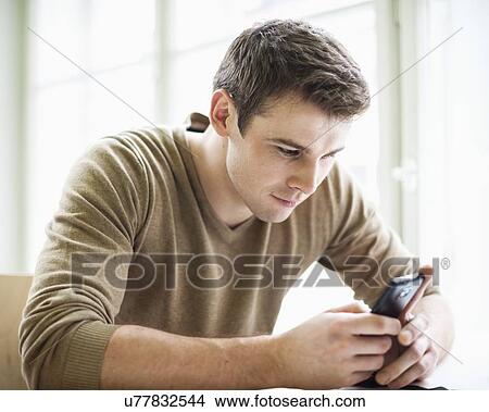 Handsome businessman using cell phone in office View Large Photo Image Picture - Handsome businessman using cell phone in office. Fotosearch
