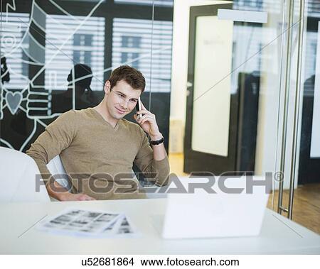 Handsome young businessman using smart phone in office View Large Photo Image Picture - Handsome young businessman using smart phone in office. Fotosearch