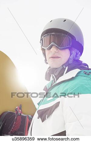 Handsome young man holding snowboard outdoors View Large Photo Image Stock Photo - Handsome young man holding snowboard outdoors. Fotosearch