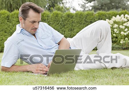 Stock Photograph - Handsome young man using laptop in park. Fotosearch