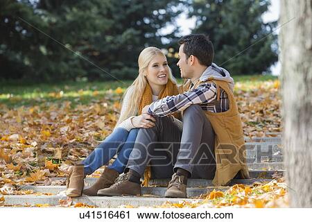 Stock Image - Happy couple communicating on steps in park. Fotosearch