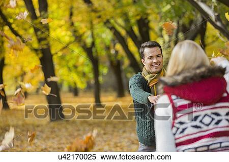 Happy couple playing with autumn leaves in park View Large Photo Image Stock Photography - Happy couple playing with autumn leaves in park. Fotosearch