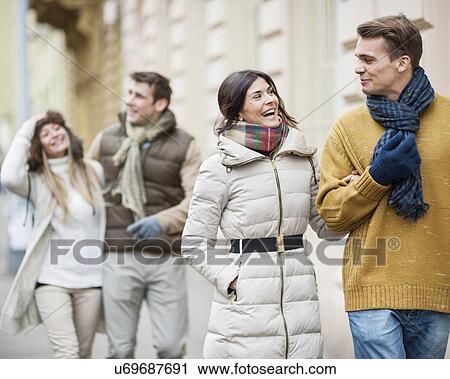Stock Image - Happy couples in warm clothing enjoying vacation. Fotosearch